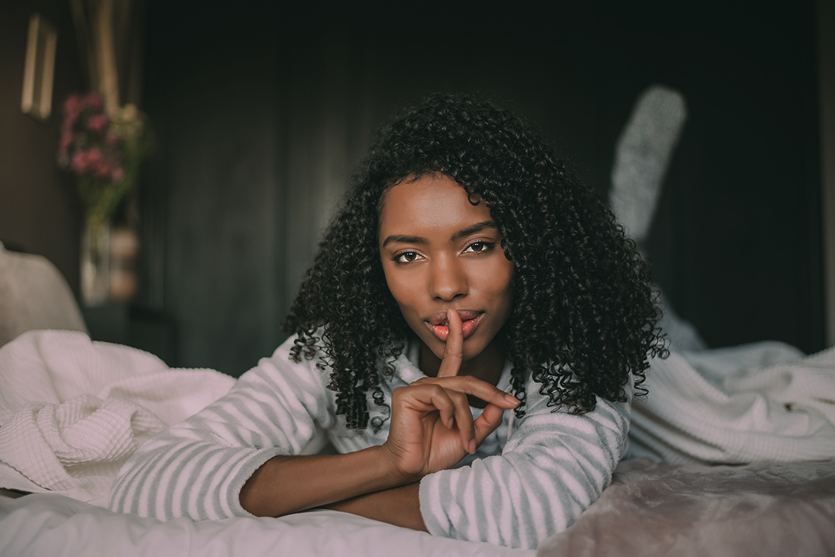 attractive black woman asking for silence with finger on lips on