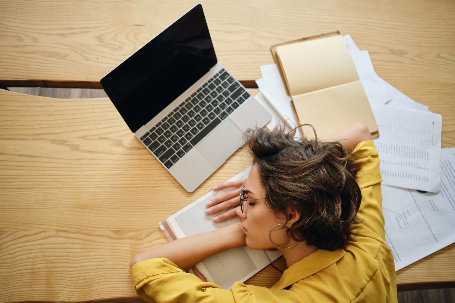 Top View Of Young Tired Woman Asleep On Desk With Laptop And Doc