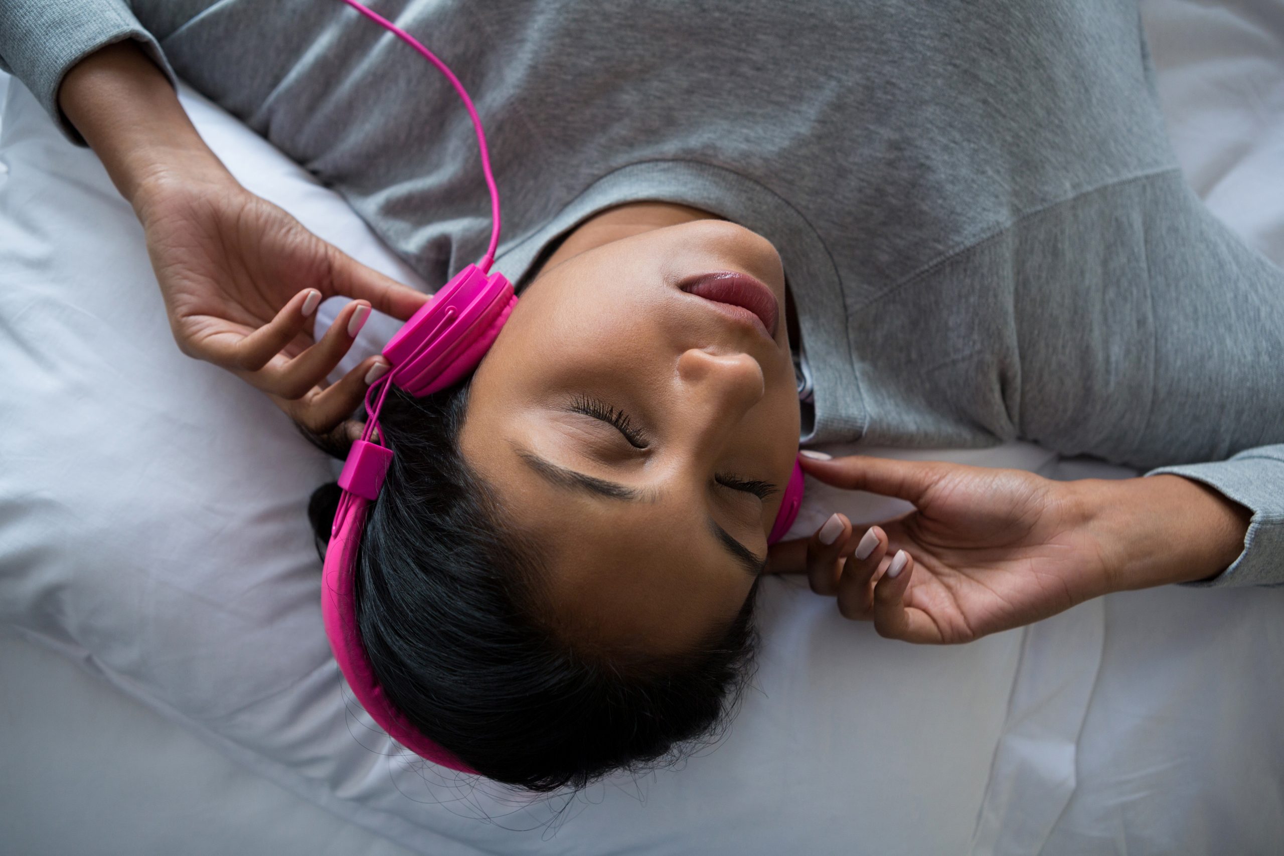 Woman listening to music while sleeping on bed